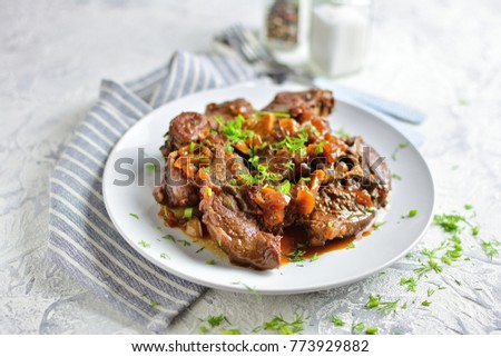 Stew, meat stew on a plate with greens, close-up, light background with ceps