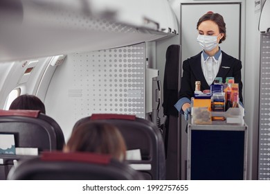 Stewardess Carrying Food Trolley In Airplane Cabin