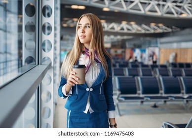 Stewardess with hand luggage and coffee in airport - Shutterstock ID 1169475403