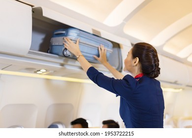 Las azafatas ayudan a los pasajeros a poner su equipaje en la cabina del avión. Guardias en el avión.