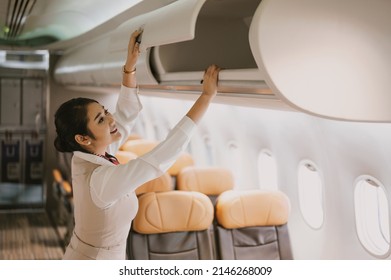 The stewardess helps the passengers to put their luggage in the cabin of the plane. Stewardess in the airplane.