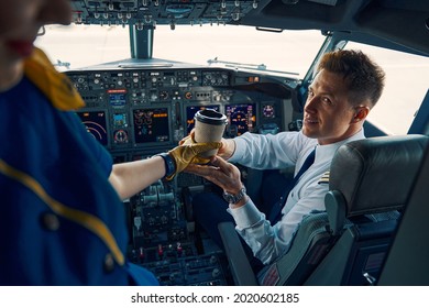 Stewardess Serving Coffee To A Pleased Co-pilot In The Cockpit