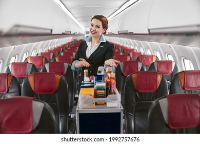 Stewardess Show Food Trolley In Cabin Of Airplane