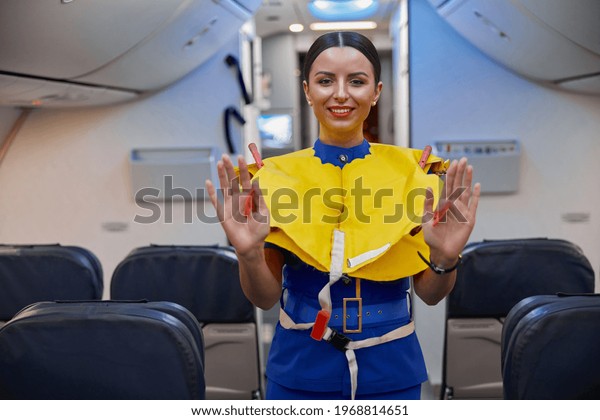 stewardess is showing safety rules before fly at\
evening plane salon