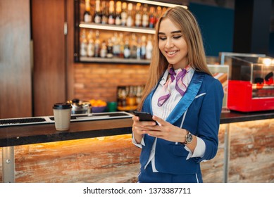 Stewardess using mobile phone in airport cafe - Shutterstock ID 1373387711