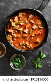 Stewed chicken livers in frying pan over black stone background. Top view, flat lay