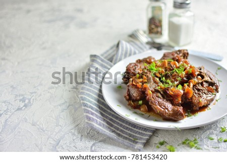 Stewed mutton in a sauce with greens, on a plate with spices, light textured background, copy space