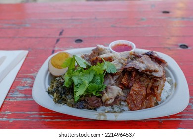 Stewed Pork Leg And Egg With Various Picked Vegetable And Steamed Rice, On Paper Dish And Rough Wooden Table. 