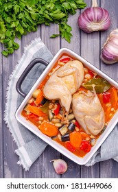 Stewed poultry with vegetables and beans in a dish on a gray wooden background. Selective focus.