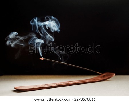 Stick Holder and Incense Stick with Smoke on Black Background. Pure relaxation theme.