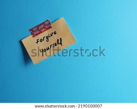 Stick note on blue copy space background with handwritten text FORGIVE YOURSELF, concept of learning to fully accept whatever you did - let go any resentment you have made significant mistakes