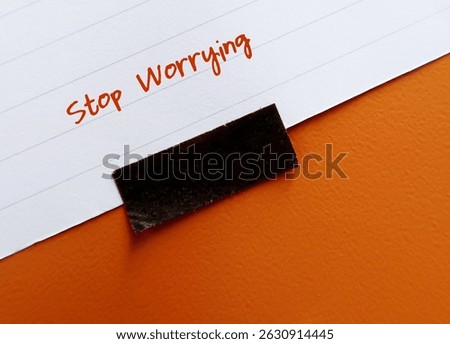 Stick note on orange background with text written STOP WORRYING - self talk to turn off anxious thoughts - to stay calm and look at life from less fearful perspective - reduce rumination