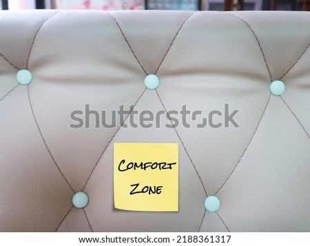 Stick note on sofa with text written COMFORT ZONE, means comfortable feel safe situation or risk free and familiar routines which you do not have to do anything new or difficult 