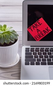Sticker note with take a break message on laptop screen. Flowerpot with green leaves.
