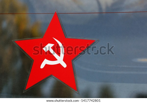 Sticker on thecar rear window as red\
five-pointed star with sickle and hammer\
emblem