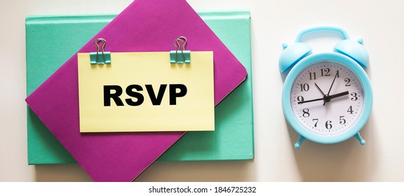 Sticker with RSVP text on colored notebooks and white background, near an alarm clock