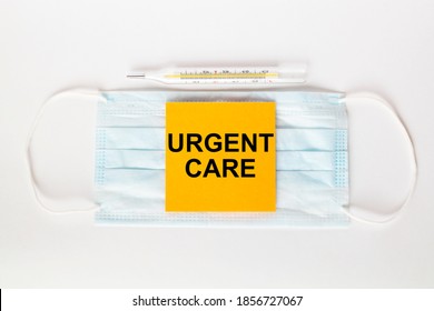 Sticker With Text Urgent Care Lying On The Mask With A Thermometer. Medical Concept