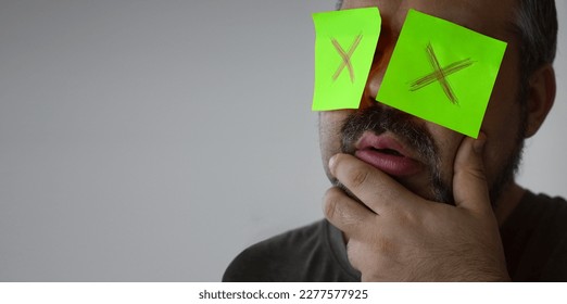 Stickers with painted crosses are glued to the eyes of a guy, a man is no looking. glued eyes. isolated white background. shocked face. unrecognizable person. forbidden information. - Shutterstock ID 2277577925
