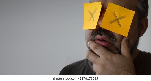 Stickers with painted crosses are glued to the eyes of a guy, a man is no looking. glued eyes. isolated white background. shocked face. unrecognizable person. forbidden information. - Shutterstock ID 2278178535