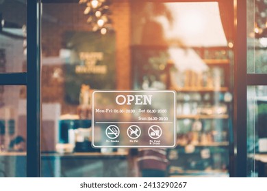 Stickers showing opening and closing times. An open sign on the front window of a coffee shop or cafe and a blurred, bokeh image inside the shop. - Powered by Shutterstock