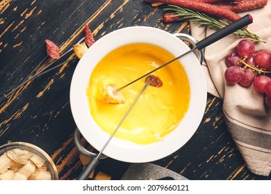 Sticks With Crouton And Sausage Dipped Into Cheese Fondue On Dark Wooden Background