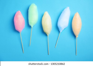 Sticks With Different Colorful Yummy Cotton Candy On Blue Background, Flat Lay 