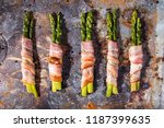 Sticks of green asparagus wrapped with bacon prosciutto ham over on old rusty background. Overhad. Top view.