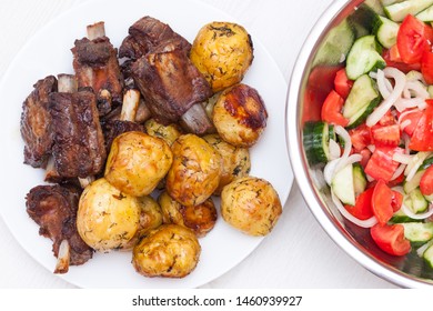 Sticky Beef Short Ribs. BBQ Ribs With Potatoes And Salad With Tomatoes And Cucumbers On White Wooden Background. Top View, Flat Lay.