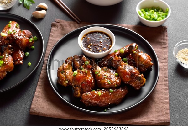 Sticky honey-soy chicken wings on plate over dark stone\
background. 