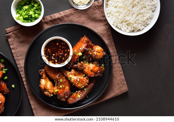 Sticky honey-soy chicken wings
on plate over dark stone background. Top view, flat lay, close
up