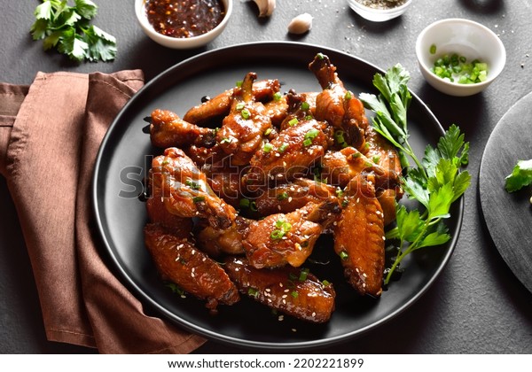 Sticky honey-soy chicken wings on plate over dark\
stone background. Close up\
view