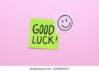 Sticky note with Good Luck handwriting on pink background.
