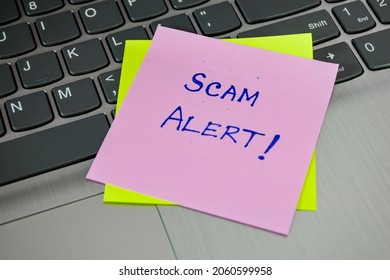 Sticky Note With Handwritten Text Scam Alert! Close Up View, Laptop Keyboard Background. 