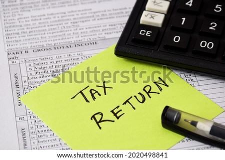 Sticky note with the handwritten text TAX RETURN placed on Income Tax Return filing form. Selective focus on the text. 