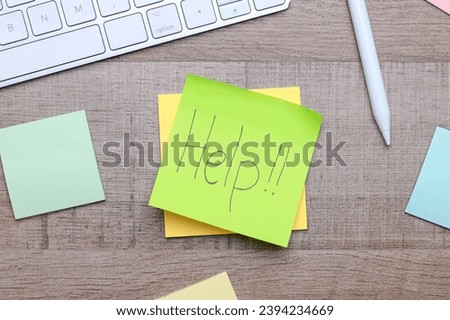 Sticky note with Help handwriting on office work desk.