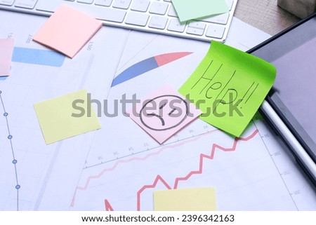 Sticky note with Help written on papers with charts diagrams and keyboard. Office work desk.