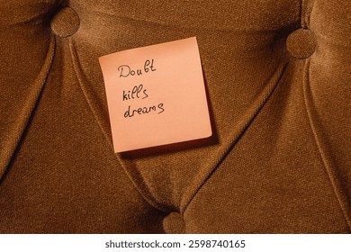 A sticky note with the message Doubt kills dreams is placed on a textured brown cushion, emphasizing the importance of self-belief and motivation, especially in personal growth.