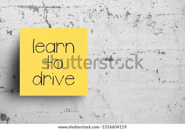 Sticky note on\
concrete wall, Learn to\
drive