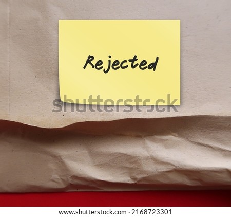 Sticky note on document envelope with handwritten text REJECTED on purple background, means refuse to agree to request, not given approval or acceptance to work or offer
