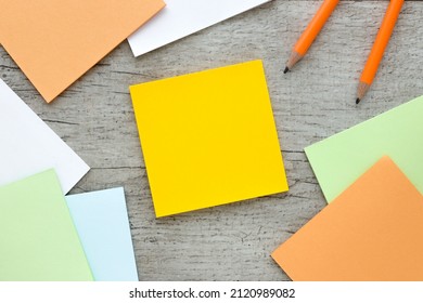 Sticky note on wood table.next to pencils and a notepad with a spring on the table.space for your text - Shutterstock ID 2120989082