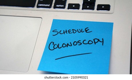 Sticky note reminder on laptop to schedule a colonoscopy                              