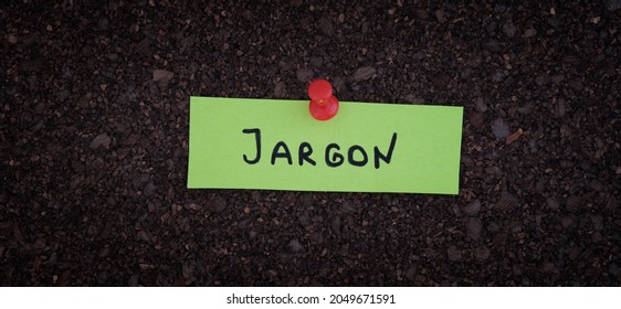 A sticky note with the word Jargon on it pinned to a cork board. Close up.