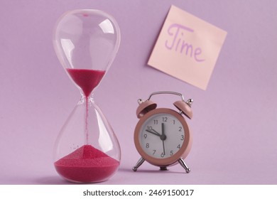 Sticky note with word TIME, hourglass and alarm clock on lilac background. Time management concept - Powered by Shutterstock