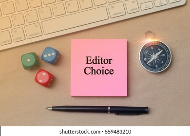 Sticky note writing Editor Choice on Office table with keyboard, dice, pen, compass