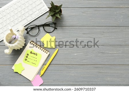 Sticky notes with to do list, computer keyboard and notebook on black wooden background. New year goals concept