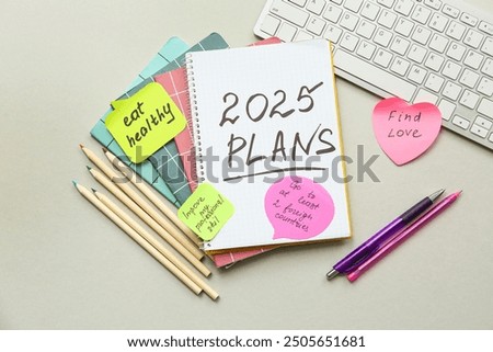Sticky notes with to do plans, notebook and computer keyboard on grey background. New year goals concept