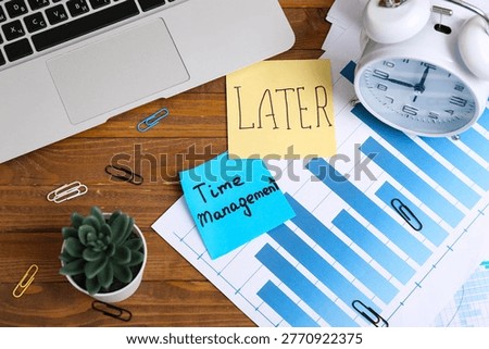 Sticky notes with text LATER, TIME MANAGEMENT, financial documents, alarm clock and laptop on wooden table