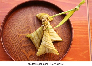 Sticky rice packed in palm leaves on a wooden plate