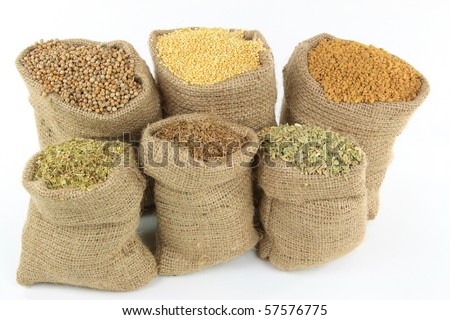 Still image of burlap sacks full with different herbs, seasonings, ingredients, and spices used in preparing food over white background.