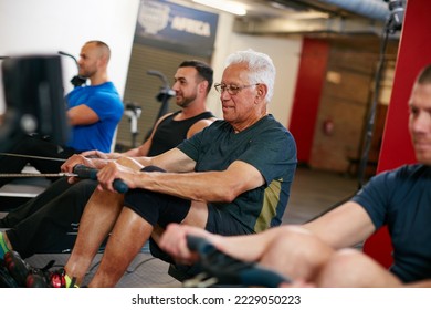 Still keeping pace with the youngsters. Cropped shot of a group of men working out on the rowing machine at the gym. - Powered by Shutterstock